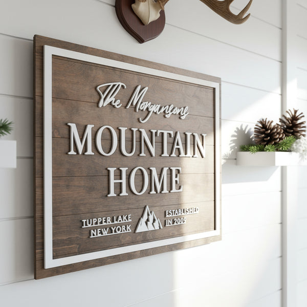 A rustic themed mountain home sign with a personalized family name hanging on a cabin wall.