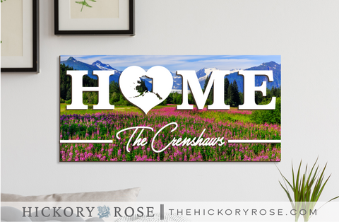 Alaska "HOME" sign with a background of the Mendenhall Glacier viewpoint, with blooming fireweed in the foreground.
