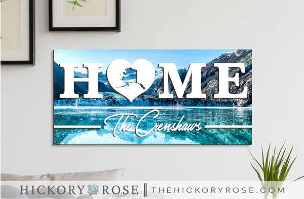 Alaska "HOME" sign with a background of Glacier Bay, blue waters and mountains.