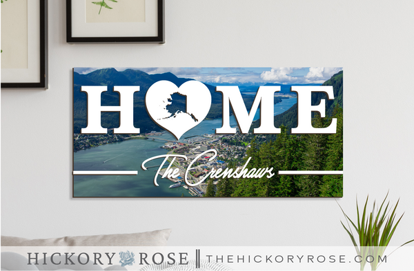 Alaska "HOME" sign with a background of an aerial view of Juneau