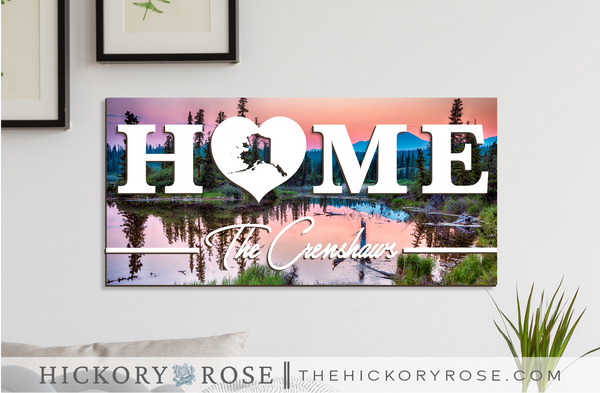 Alaska "HOME" sign with a background of St. Elias Park at sunset.